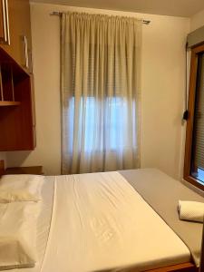 a white bed in a bedroom with a window at Cozy Modern Apartment Podgorica in Podgorica