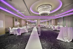 une salle de banquet avec des tables et des chaises blanches et un éclairage violet dans l'établissement Park Inn By Radisson Istanbul Ataturk Airport, à Istanbul 76 autres photos
