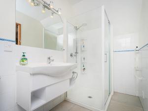 a white bathroom with a sink and a shower at The Mount Paku Bach - Tairua Holiday Home in Tairua +34 photos