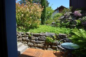 a garden with a stone wall and a table and chair at BnB chez Fanfan in Morges