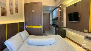PampangにあるApartemen VidaView Unit 26C By Millproの白いベッドとテレビのある寝室