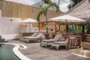 a patio with chairs and umbrellas next to a pool at Layla Cabana - 7BR Villa in Pererenan - With Private Pool, Spa, Cinema & Gym in Tumbak Bayuh