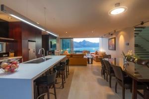 a kitchen and living room with a counter and chairs at Villa De Luxe, a Relax it's Done luxury holiday home in Queenstown