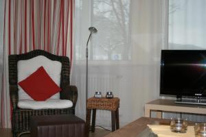 a living room with a chair with a red pillow at Seewiese 01 Seeblick mit Hochschwarzwald-Card in Titisee-Neustadt +16 photos