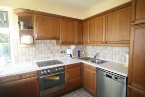 a kitchen with wooden cabinets and a sink at Seewiese 01 Seeblick mit Hochschwarzwald-Card in Titisee-Neustadt