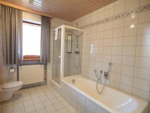 a bathroom with a shower and a tub and a toilet at Cozy Apartment in Ruhmannsfelden with Swimming pool in Achslach +54 photos
