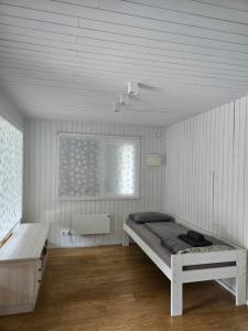 a white room with a bed and a window at Vasarnieki 24 in Ziemupe