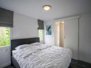 a bedroom with a large white bed with a window at Lovely Holiday Home in Kattendijke near Centre in Kattendijke +25 photos