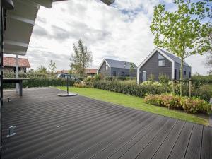 a wooden deck in a yard with a house at Lovely Holiday Home in Kattendijke near Centre in Kattendijke