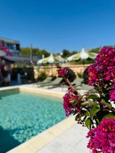 una piscina con flores y sombrillas púrpuras en Villa Casa Nova, en Balchik