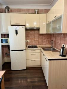 a kitchen with white cabinets and a white refrigerator at Doba In Ua Lux Apartments in Dnipro +2 photos