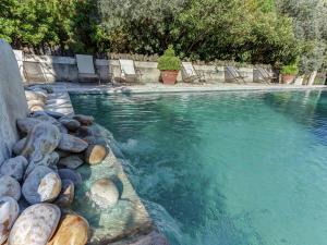 a swimming pool with chairs and rocks in the water at Charming Cottage in Oppède amidst Vineyards in Maubec +30 photos