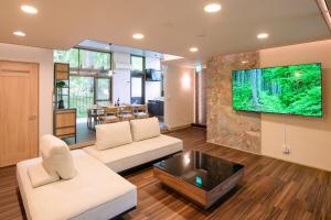 ein Wohnzimmer mit einem Sofa und einem Fernseher an der Wand in der Unterkunft Serenity Springs Villa Morita in Hakone