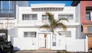 una casa blanca con una palmera delante en Villa de luxe vue sur mer, en Moulay Bousselham