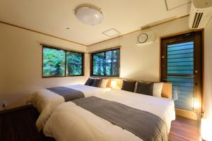 2 Betten in einem Schlafzimmer mit 2 Fenstern in der Unterkunft Serenity Springs Villa Morita in Hakone