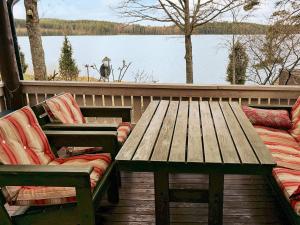 a wooden table and chairs on a deck with a lake at 4 person holiday home in VETLANDA in Lillarp +9 photos