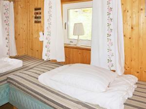 a bed in a room with a window and a bed sidx sidx sidx at 4 person holiday home in Vetlanda in Lillarp