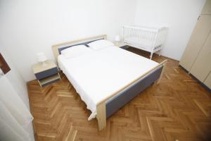a bedroom with a white bed and a wooden floor at Apartments Roza in Miškovići