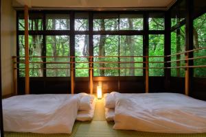 zwei Betten in einem Zimmer mit Fenster in der Unterkunft Serenity Springs Villa Morita in Hakone