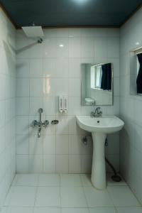 a white bathroom with a sink and a mirror at The solace pahalgam in Pahalgām
