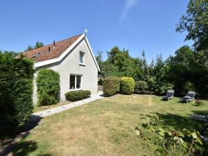 una casa blanca con dos sillas en un patio en Cozy Holiday Home in Zonnemaire near lakebeach, en Zonnemaire