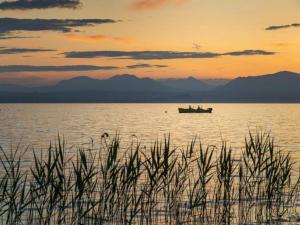 a boat in the middle of the water at sunset at Vibrant Holiday Home in Lazise with Swimming Pool near 2 Lakes in Lazise