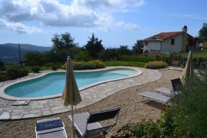 a swimming pool with two lawn chairs and an umbrella at Agriturismo il Roccolo in Pantasina +43 photos