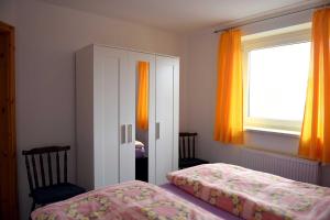 a bedroom with a bed and a window with orange curtains at Annabell in Kühlungsborn