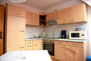 a kitchen with wooden cabinets and a white microwave at Annabell in Kühlungsborn +1 photo