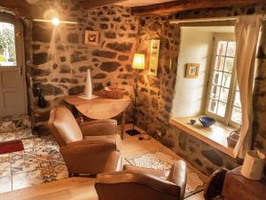 un salon avec des murs en pierre et des chaises et une table dans l'établissement Cozy Countryside Escape in Auvergne, à Vachelerie