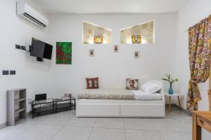 Cette chambre blanche dispose d'un lit et de trois fenêtres. dans l'établissement Casa Giniusa by Wonderful Italy, à Catane