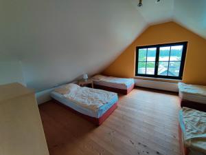 a attic room with three beds and a window at Spacious semi-detached house with wood stove located directly on the Rennsteig in Eisfeld +130 photos