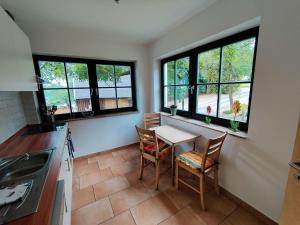 a kitchen with a table and two chairs and windows at Spacious semi-detached house with wood stove located directly on the Rennsteig in Eisfeld