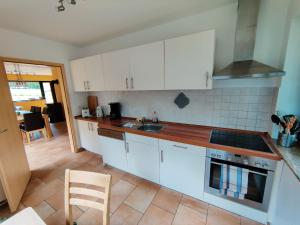 a kitchen with white cabinets and a stove top oven at Spacious semi-detached house with wood stove located directly on the Rennsteig in Eisfeld