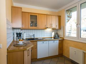 a kitchen with wooden cabinets and a sink and a window at Large apartment in the beautiful Sauerland with garden, patio and sauna in Erndtebrück