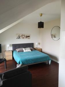 ein Schlafzimmer mit einem blauen Bett und einem Sofa in der Unterkunft Appartement dernier étage terrasse et parking in Carantec