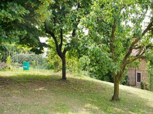 two trees in a field with a building in the background at Holiday home in Asti with a lovely hill view from the garden in Moncucco Torinese