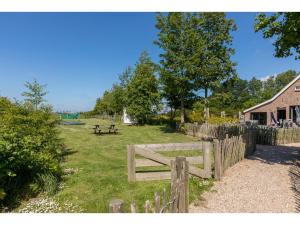 Una valla de madera junto a un campo con una mesa de picnic. en Family house with an ideal location, private terrace, garden and sauna, en Vrouwenpolder