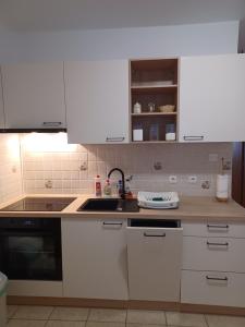 a kitchen with white cabinets and a sink at Apartmani Tomičić in Malinska