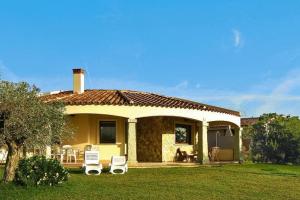 una pequeña casa amarilla con un patio de césped en Flat with barbecue in Castiadas, en Costa Rei