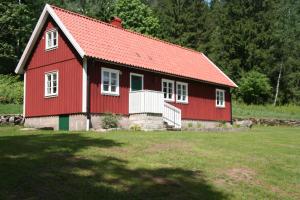 une maison rouge avec un toit rouge dans un champ dans l'établissement Wråen Svartrå, à Svartrå