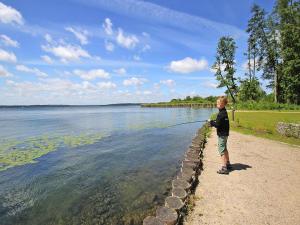 een jongen staat aan de oever van een meer te vissen bij Apartment Hafenflair am Plauer See, Plau am See in Plau am See
