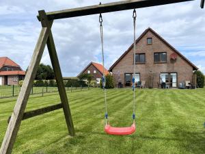 a swing in a yard with a house at Geraeumige Ferienwohnungen mit eigener Terrasse, Neßmersiel in Neßmersiel +5 photos