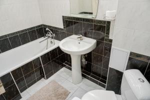 a bathroom with a sink and a tub and a toilet at Doba In Ua Centre Apartments in Dnipro +14 photos