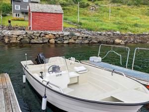 a white boat docked at a dock with a red building at 8 person holiday home in Barmen in Barmen