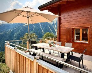 a wooden deck with a table and an umbrella at Chalet Poiema in Bellwald