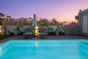 a swimming pool with two chairs and an umbrella at Gournes - NewTown Residences in Gournes
