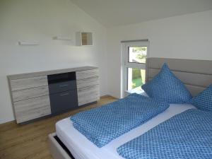 a bedroom with a bed with blue pillows and a dresser at Sunny house, 2 residential units in Postmünster