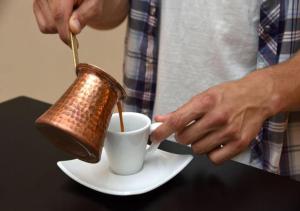 a man pouring coffee into a cup on a table at Poseidon Athens Hotel in Athens +51 photos