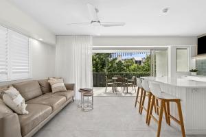 ヌーサヘッズにあるFrench Quarter by Stay Noosaのソファとテーブルのあるリビングルームとキッチン